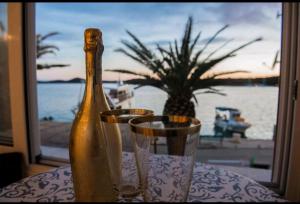 een fles champagne zittend op een tafel met twee glazen bij Apartman Cezar2 in Rogoznica