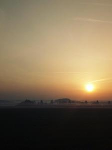 una puesta de sol con el sol saliendo sobre un campo en Gîte au bord de la rivière en Frangy-en-Bresse