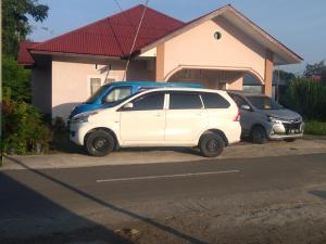 zwei Autos auf einem Parkplatz vor einem Haus geparkt in der Unterkunft Zahra Syariah Home Stay in Bukittinggi