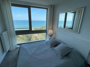 sypialnia z łóżkiem i dużym oknem w obiekcie PINEA Apartments Pobierowo z niesamowitym widokiem na morze oraz jacuzzi w wybranych apartamentach w Pobierowie