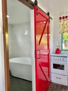a red door in a bathroom with a tub and a stove at Sea Kecil Tiny House near Jetty of Kuala Besut in Kampong Nail