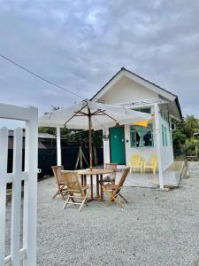 a house with a table and chairs and an umbrella at Sea Kecil Tiny House near Jetty of Kuala Besut in Kampong Nail