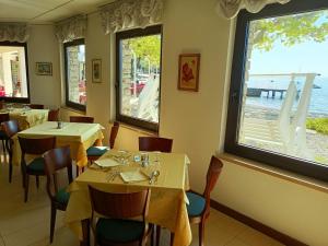 ein Restaurant mit Tischen, Stühlen und Fenstern in der Unterkunft Hotel S.Maria in Brenzone sul Garda