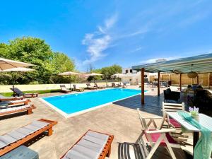 een zwembad met stoelen en een tafel en een zonneklep bij Beach Villa Verano with private pool by DadoVillas in Sidari