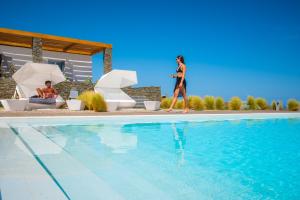 a woman walking next to a swimming pool at Elements Sifnos Boutique in Faros