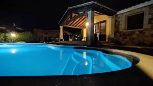 a blue swimming pool in front of a house at night at Villa Janas con piscina privata Budoni in Tanaunella