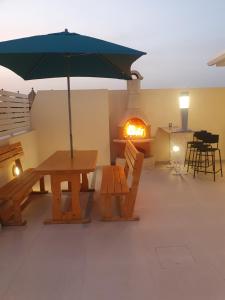 un patio con mesa, sombrilla y chimenea en B&S Accommodation Penthouse 602 en Hal Ghaxiak