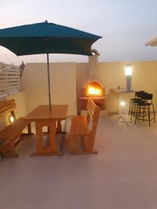 a patio with a table and an umbrella and a fireplace at B&S Accommodation Penthouse 602 in Hal Ghaxiak