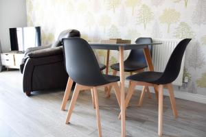 una mesa y sillas en una sala de estar con sofá en Queens Lodge - Beautiful Modern House with Free Parking - Marvello Properties, en Norwich