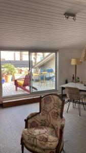 a living room with a chair and a view of a patio at La Terrasse du Bois Plage in Le Bois-Plage-en-Ré