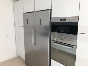 einen Kühlschrank aus Edelstahl in einer Küche mit weißen Schränken in der Unterkunft Casa do Barroso in Cabeceiras de Basto