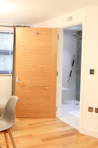 a wooden door in a room with a shower at Lovely Studio Apartment with access for Wheel-chairs in Sydenham in Forest Hill