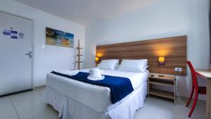 a bedroom with a large bed and a table and a desk at Hotel Refugio in Maceió
