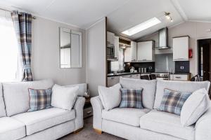a living room with two couches and a kitchen at Pentire Coastal Holiday Park in Bude +31 photos