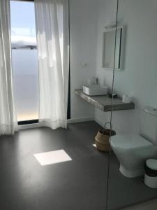 een witte badkamer met een toilet en een wastafel bij Salema in Punta de Mujeres