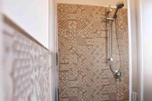 a shower in a bathroom with a tile wall at Madrice 66 Central Rooms in Favignana