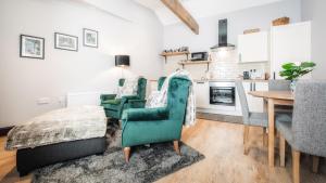 a living room with two green chairs and a table at The Old Milking Parlour in Barmston +6 photos