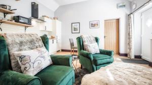 a living room with two green chairs and a table at The Old Milking Parlour in Barmston
