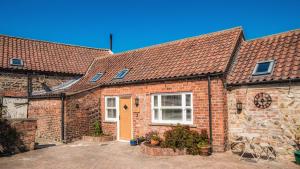 a red brick house with a yellow door at The Old Milking Parlour in Barmston