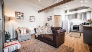 a living room with a leather couch and a chair at The Old Tractor Shed in Barmston