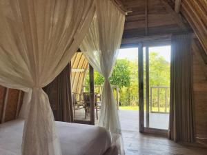 a bedroom with a bed and a large glass door at The Ulus Klumpu in Uluwatu