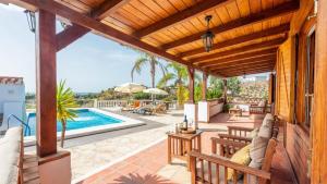 un patio extérieur avec une piscine et une pergola en bois dans l'établissement Cortijo La Tata Almayate Alto by Ruralidays, à Almayate Alto