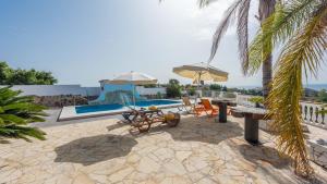 un patio avec chaises et parasols à côté d'une piscine dans l'établissement Cortijo La Tata Almayate Alto by Ruralidays, à Almayate Alto