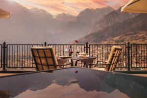een tafel en stoelen op een balkon met uitzicht op de bergen bij Hotel Castel Mani in San Lorenzo in Banale