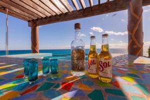 three bottles of beer sitting on a table with glasses at Casa Cielo Studio 1 with Tropical Garden Patio in Isla Mujeres