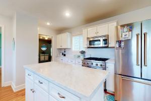 a kitchen with white cabinets and a stainless steel refrigerator at Rocky Beach House by the Cove in Seaside