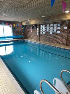 a large swimming pool with blue water in a building at Poolside in Peacehaven