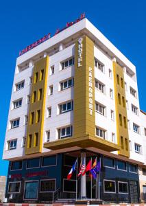 een hotelgebouw met vlaggen ervoor bij Hotel L'Aéroport in Nador