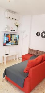 Duplex Calle Padre Lerchundi في تشايبيونا: غرفة معيشة مع أريكة حمراء وتلفزيون بشاشة مسطحة