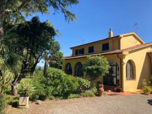 una casa amarilla con árboles y un patio en Tenuta Poggio alla Farnia en Fauglia