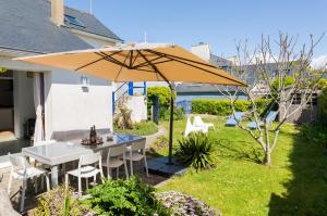 a patio with a table and an umbrella at Kan ar Moor et sa vue Mer exceptionnelle! in Pouldreuzic