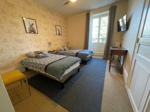a bedroom with two beds and a desk and a window at Les Lodges du Castel in Châteauvillain