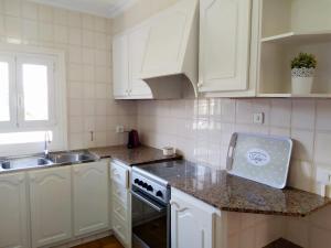 uma cozinha com armários brancos, um lavatório e um fogão em Villa Ferrer em Port d'Addaia