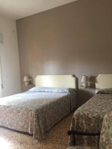 a hotel room with two beds and two lamps at Nonna Sonia in Castiglione della Pescaia
