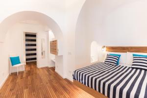 a white room with a bed with blue and white stripes at Lampara Mare in Vico Equense