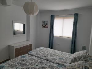 1 dormitorio con cama, espejo y ventana en Apartamento ULISES 2A, en Valle Gran Rey