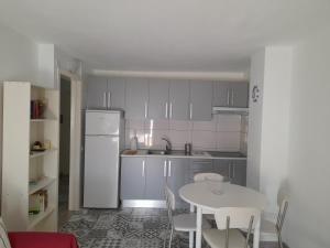 cocina con mesa, sillas y nevera blanca en Apartamento ULISES 2A, en Valle Gran Rey