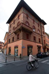una mujer montando una bicicleta delante de un edificio en 45 - Tourist House Bologna Oberdan - Self check-in en Bolonia