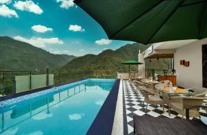 a resort pool with tables and chairs and a view at Vyom Boutique Hotel Rishikesh in Rishīkesh