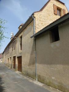 un vieux bâtiment sur le côté d'une rue dans l'établissement Gîte la grange, à Domme