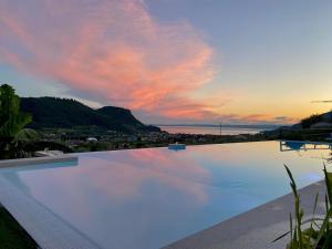 a large swimming pool with a sunset in the background at Relais Villa Olivi in Costermano