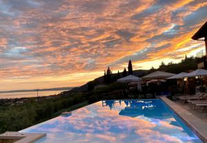 een zwembad met een zonsondergang in de lucht bij Relais Villa Olivi in Costermano