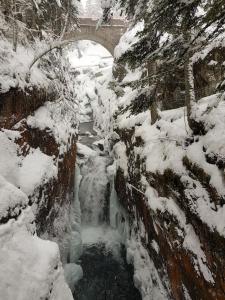eine schneebedeckte Brücke mit einem Wasserfall im Schnee in der Unterkunft Le petit montagnard in Cauterets
