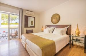 a bedroom with a large bed and a balcony at Hotel Vale Da Telha in Aljezur