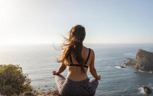 a woman doing yoga on a cliff overlooking the ocean at Hotel Vale Da Telha in Aljezur