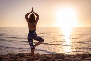 a woman doing a yoga pose on the beach at Hotel Vale Da Telha in Aljezur
